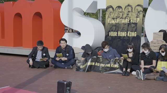 活动的参与者们围坐在广场上合唱《愿荣光归香港》