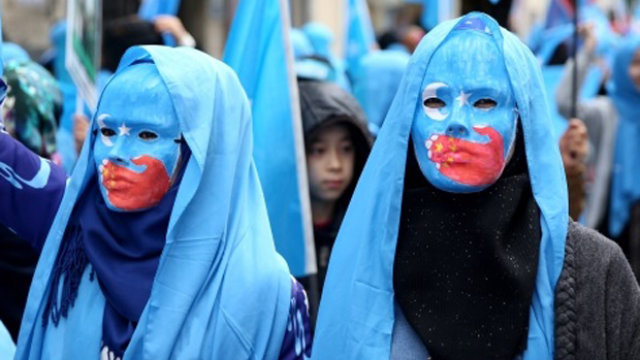 维吾尔人戴着讽刺中国打压维吾尔族人的面具示威