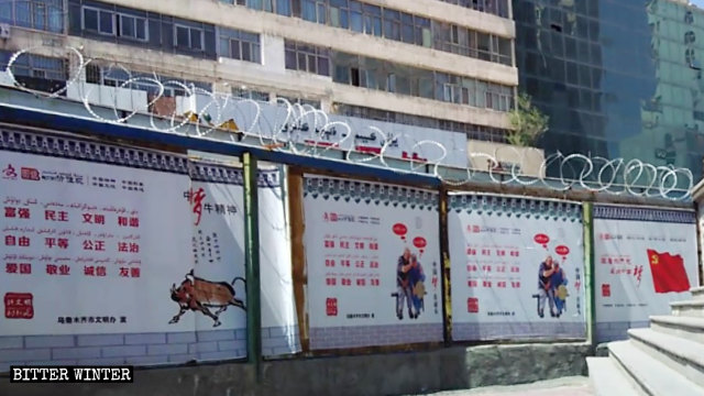 一布满了铁丝网的围墙上悬挂着习近平「中国梦」的宣传海报